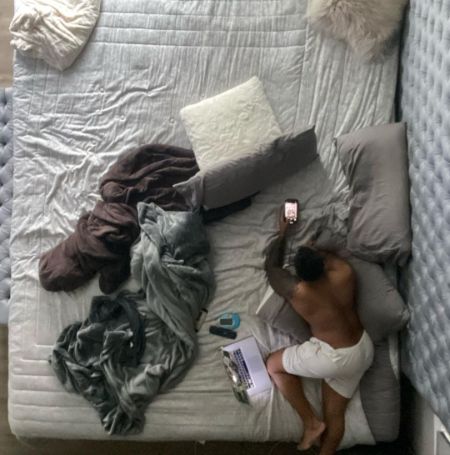 Deon Cole posed on his bed in his house.